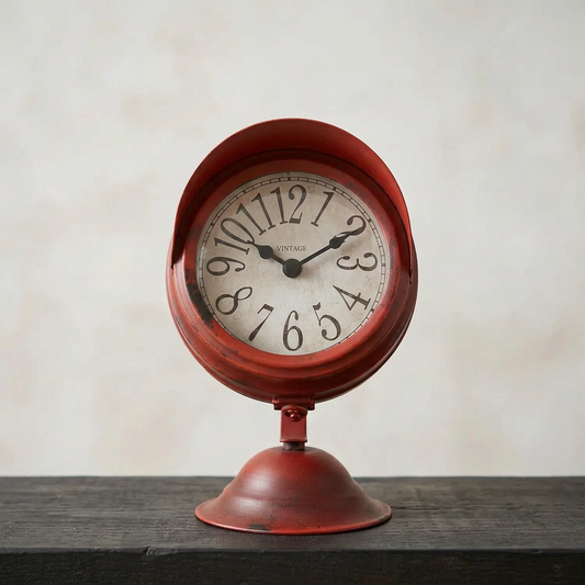 Front-facing clock on a dark timber shelf against pale limewash