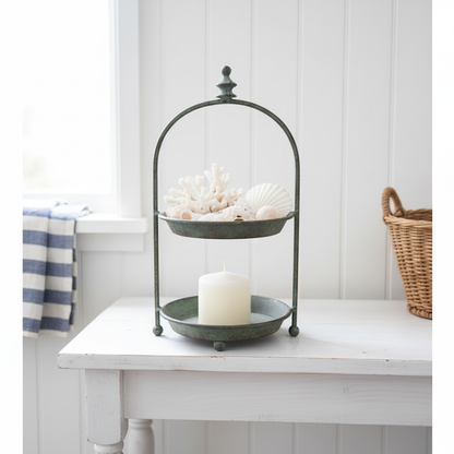 Verdigris two-tier stand holding shells, coral and a candle on a white console in a Hamptons coastal beach house — vintage metal display tray