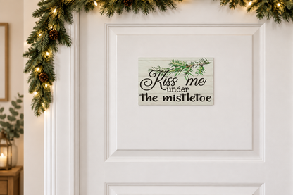 Kiss Me Under the Mistletoe sign on a decorated doorway