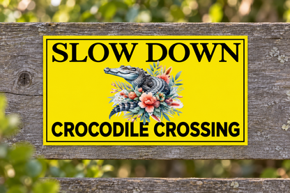 Slow Down Crocodile Crossing sign on a weathered roadside timber fence