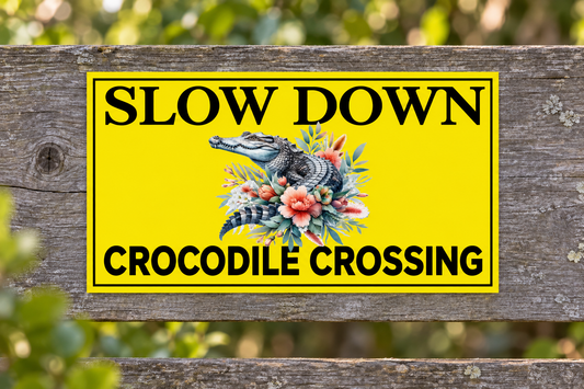 Slow Down Crocodile Crossing sign on a weathered roadside timber fence